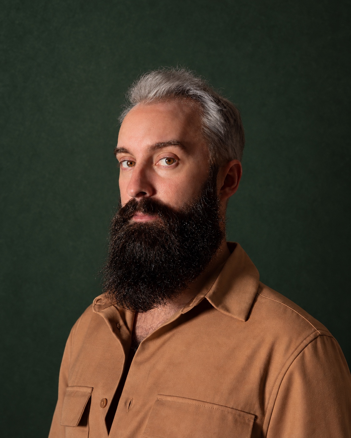 Dylan in a tan shirt against a forest-green background